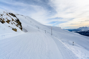 Snowy mountain slopes, a view from above of ski trails and cable cars.