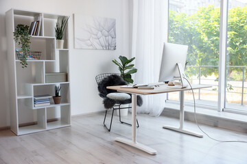 Home workspace. Modern computer, houseplant and stationery on wooden desk indoors