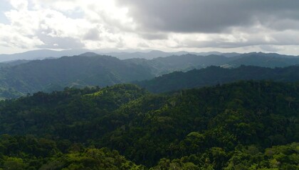 Fototapeta premium Lush Green Mountain Range Under Cloudy Sky.