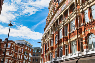 Red brick building with decorative stonework and arched windows in London, UK.