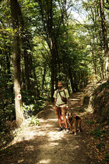 Fototapeta premium Man hiking with German Shepherd on forest trail in Fruska Gora National Park, Serbia. Front view portrait. Hiking with pet concept.