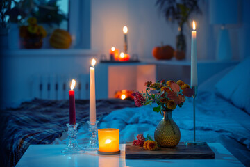 autumnal chrysanthemum in vase with burning candles in bedroom