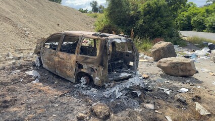 Burnt-out minivan in a littered area