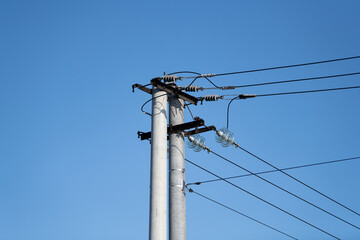 A utility pole stands tall with power lines stretching across a bright blue sky. The scene captures the infrastructure essential for electricity distribution