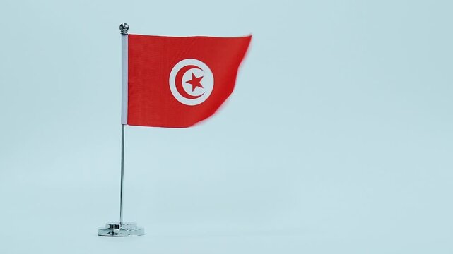 Slow motion video of Tunisian table flag waving on white background