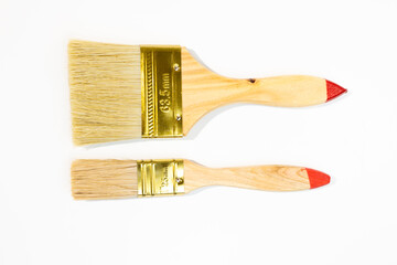Two wooden handled paintbrushes with red tips and golden ferrules Isolated - on  white background. One brush is larger than the other. 