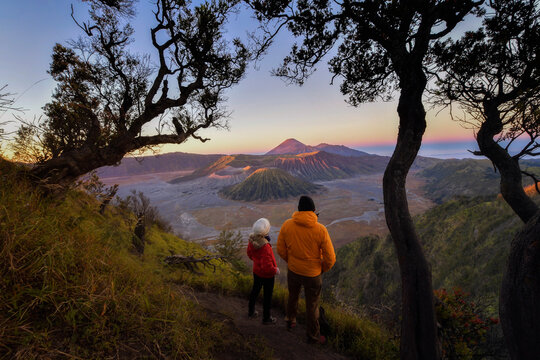 Rear view of two adults looking at Mt Bromo (Gunung Bromo) at sunrise from Mt Penanjakan, Bromo Tengger Semeru National Park, East Java, Indonesia
