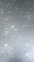 
Close-up of raindrops on a smooth gray surface. Water droplets create natural abstract texture, symbolizing freshness, weather, moisture, and rainy atmosphere for backgrounds or design elements.