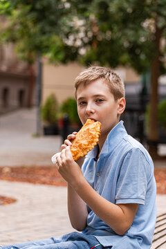 Close-up portrait of a teenage boy eating a traditional Fried meat pie (Chebureki), Tbilisi, Georgia