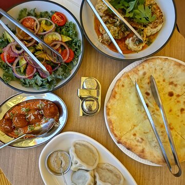 Traditional Georgian khinkali with walnut sauce and Imeruli khachapuri, beef croquettes and a cauliflower steak with romanesco sauce and a kale, tomato, onion and avocado salad on a table