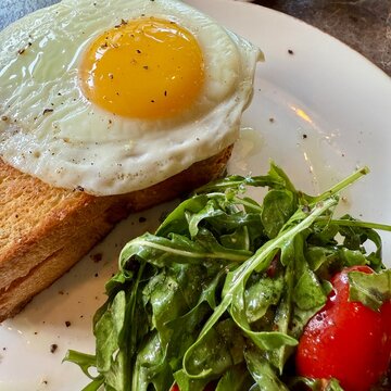 Close-up of a croque madame with a fried egg and mixed salad