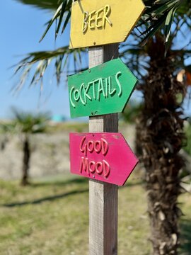 Close-up of colourful wooden directional beer, cocktails and good mood signs on a beach