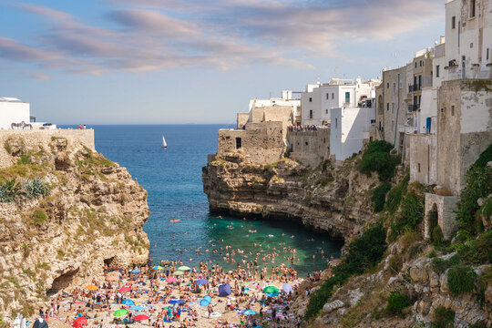 Crowded beach and Cliffside Houses along the Adriatic Coast, Polignano a Mare, Bari, Puglia, Italy