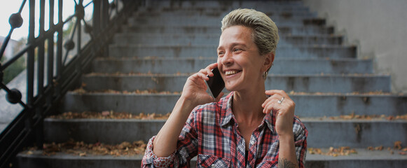Portrait of smiling woman talking on smartphone on stairs in city