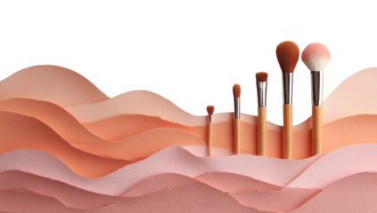 Makeup brushes arranged on a layered, wavy background of peach and blush-colored paper