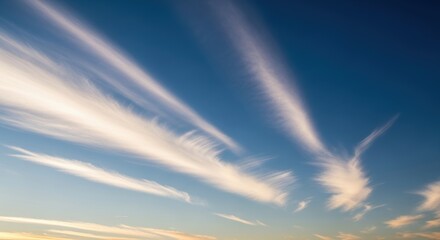 Wispy cirrus clouds stretching across a clear blue sky at sunset