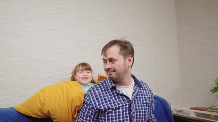 Happy father daughter play carefree at home in room hitting each other with pillows. Happy family, child dad have fun playing pillow fight on couch, laughing together. Family weekend parent child home - Powered by Adobe
