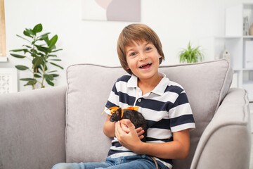 Dreams come true. Happy boy with pet rat on armchair at home