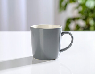 Obraz premium Gray Mug on White Table with Green Plant Background, Minimalist Style.