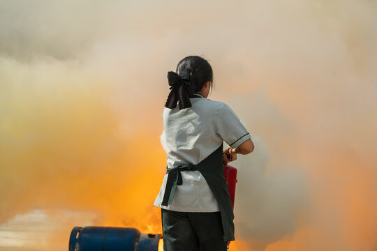Woman showing how to use a fire extinguisher on a training for employees industry.Basic fire fighting and evacuation fire drill simulation training for safety industrial.Fire fighter concept.