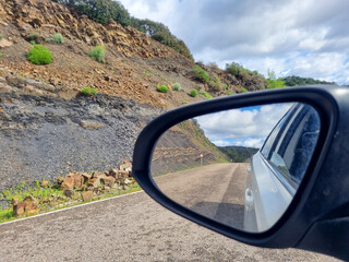 Conceptual image of travel, road seen from the car mirror