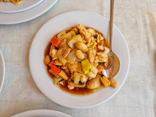 A plate of chicken with almonds on a white matte table