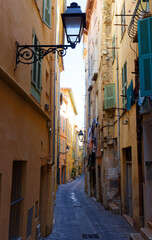 Narrow street in the historic center of the southern French city of Menton with stone houses and colorful facades