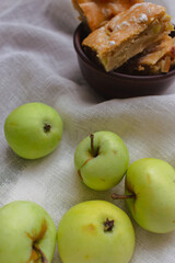 Apple pie with powdered sugar with green apples. Autumn dessert. Homemade dessert. Apple pie with cinnamon and fresh apple fruits. Country still life. Sweet dessert. Homely vibes. 