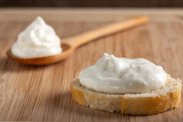 Creamy fresh cheese spread on rustic bread with wooden spoon.