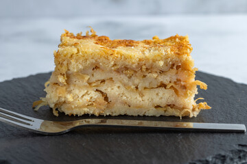 Moist layered apple semolina pie with crispy golden topping and fork.