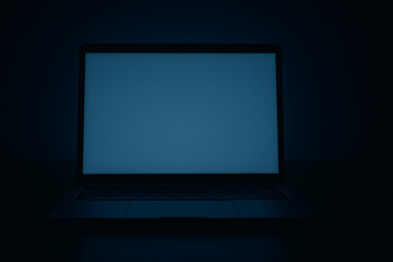 Dark unlit laptop screen glowing faint blue in moody low light environment cybersecurity hacking concept empty digital workspace blank display for technology thriller cinematic suspense scene night co