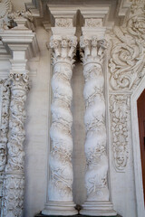 Beautiful white plaster molding in the form of columns with twining branches and leaves on a clear sunny day. Sights of Moscow, World tourism.