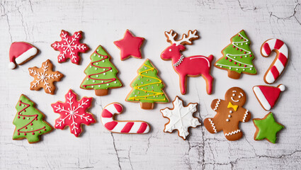 Christmas cookies in festive shapes including trees, snowflakes, stars, reindeer and gingerbread man on white textured background