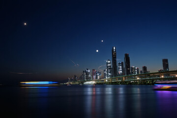 Naklejka premium Night cityscape of Hong Kong's downtown skyline with colorful skyscraper lights reflecting on the water