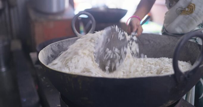 Cinematic cooking shot of poha being dry roasted in a wok, highlighting the Indian farsan-making process and the homemade snack culture
