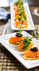 Appetizing salmon canap?s, several on a white platter, arranged in a row