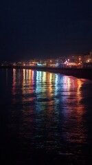 Obraz premium Colorful lights reflecting on the water at night in brighton
