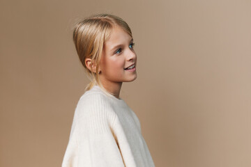 Portrait of a young girl in a soft knit sweater, gazing to the side with a gentle smile. Warm...