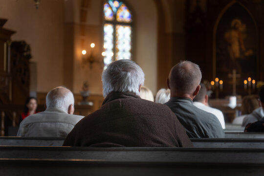 Group of People Sitting in Church Pews During Service, Back View