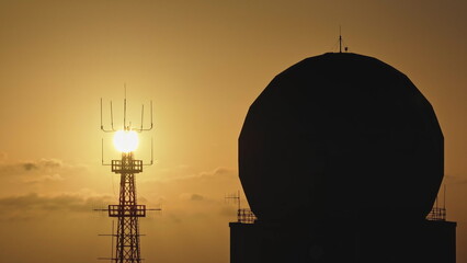 Malta: Golden sunset illuminating radio towers and a radar antenna, creating a striking silhouette against the colorful sky in Malta. Drone flight