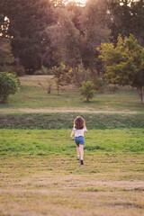 Running freely through nature as the sun sets over a serene landscape in late afternoon, a child explores the joy of the outdoors