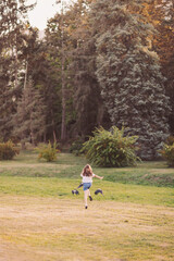 Joyful child twirls freely on a sunny afternoon in a lush green park filled with tall trees and soft grass