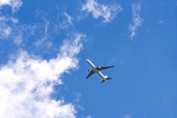 Passenger airplane flying in blue sky with clouds, travel and aviation concept