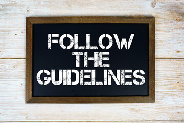 Naklejka premium Follow the Guidelines text written on blackboard flat lay on wooden background