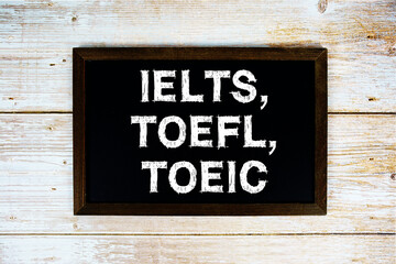IELTS, TOEFL, TOEIC text with gift box present and alarm clock on black background