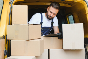 Delivery driver checking packages in van with clipboard
