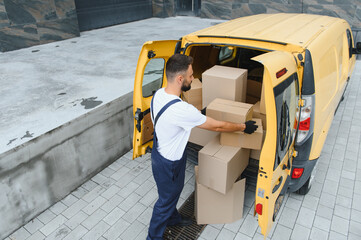 Courier loading cardboard boxes into delivery van