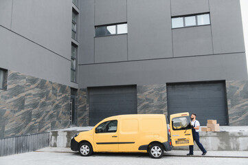 Delivery driver unloading cardboard boxes from yellow van