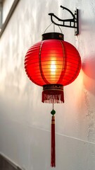 Red paper lantern, lit, hanging from a white wall