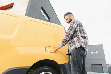 Delivery driver opening fuel tank cap of yellow van